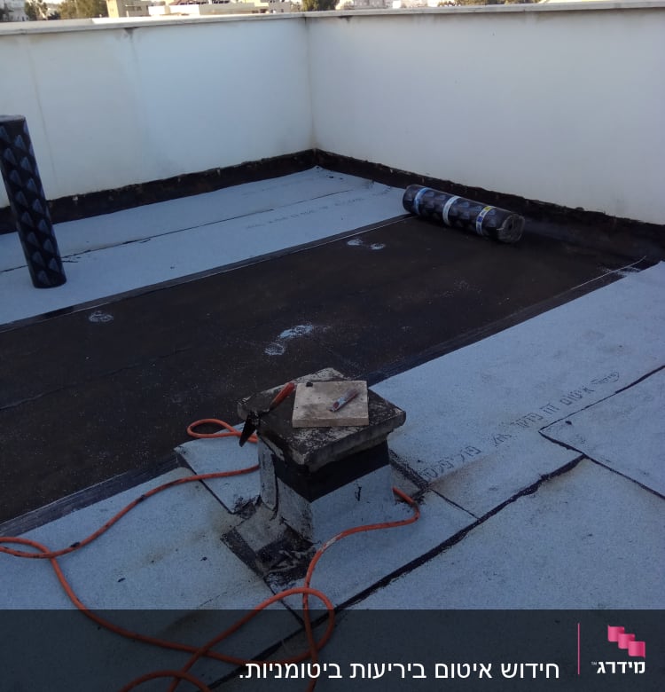 גג עם יריעות איטום, כבל חשמלי וכלי עבודה